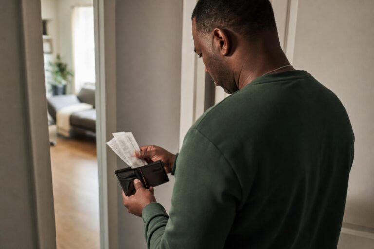 Man with bipolar disorder reviews spending receipts in a morning hallway.