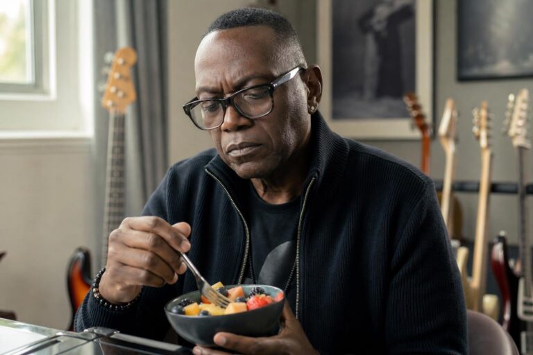 Randy Jackson-inspired musician pauses thoughtfully in a music room while managing diabetes.