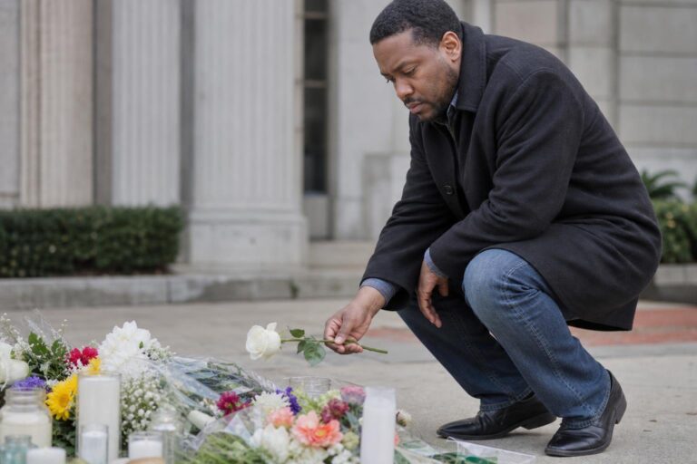 Black man places a flower at a memorial after Don Cornelius’ death was ruled suicide.